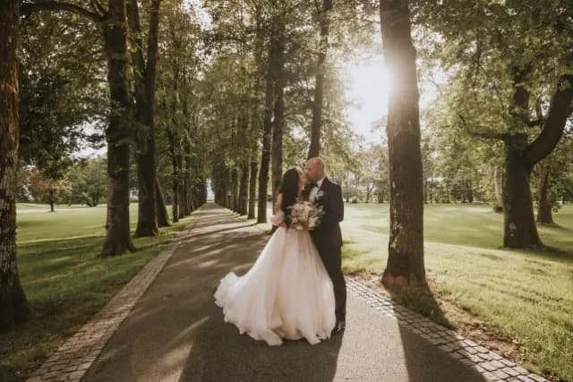 Mladoporočenca med poljubom v drevoredu, fotografija s poroke